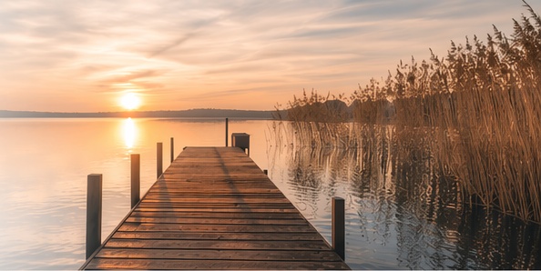 Ruhiger See mit Steg im Sonnenuntergang